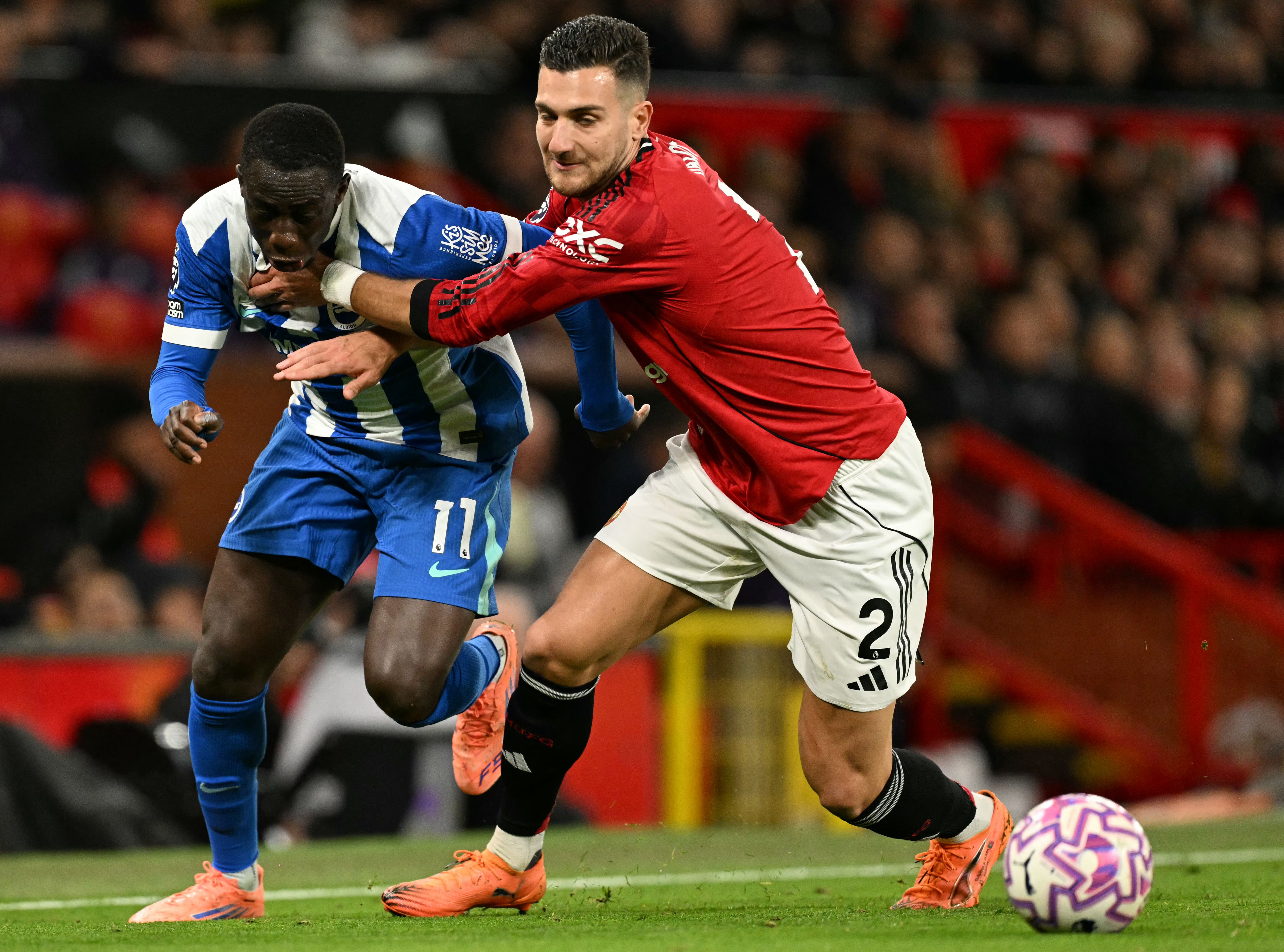 Yankuba Minteh (L) battles with Manchester United's Portuguese defender #02 Diogo Dalot (R) 